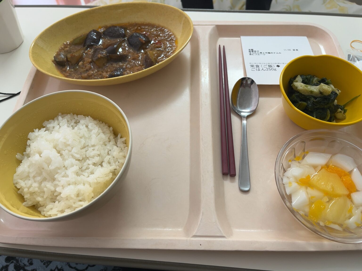 「病院食の昼食（ご飯・麻婆茄子・青菜の和え物・フルーツ入りデザート）」