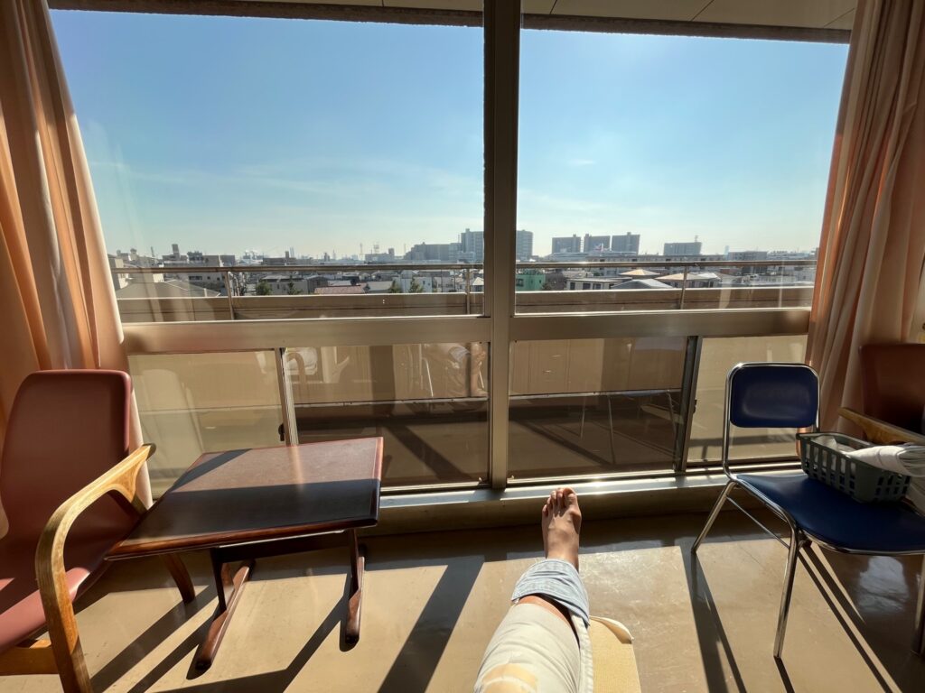 病室の窓際で日の光を浴びながら外を眺める様子